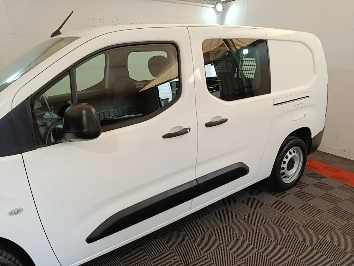 Vue de profil côté gauche du Peugeot Partner blanc avec portes coulissantes et protections latérales noires.