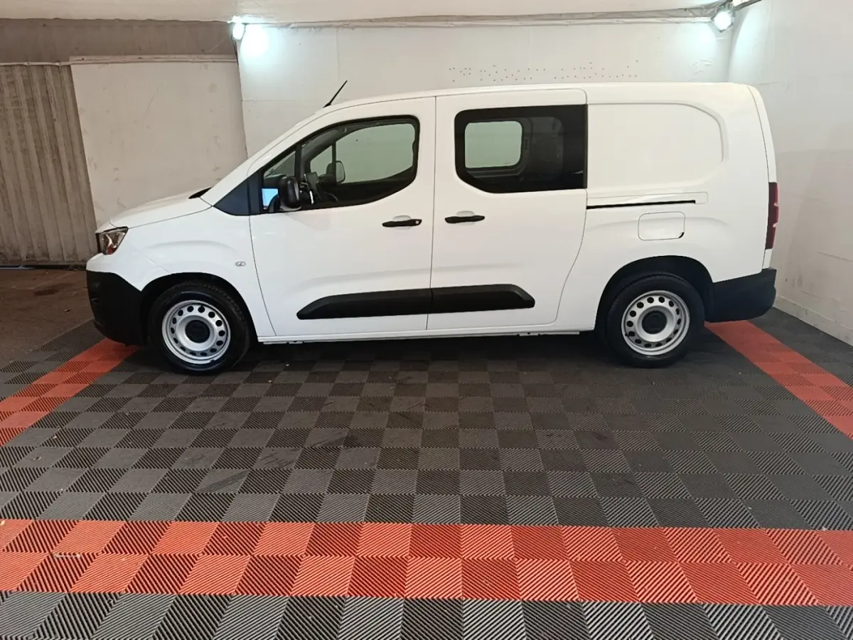 Vue de profil côté gauche d’un utilitaire Peugeot Partner blanc avec portes latérales et jantes acier simples.