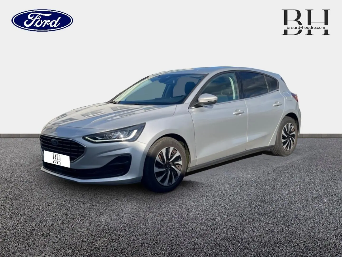 Ford Focus 2023 gris lunaire métallisé vue 3/4 avant droit avec calandre noire et jantes bicolores.