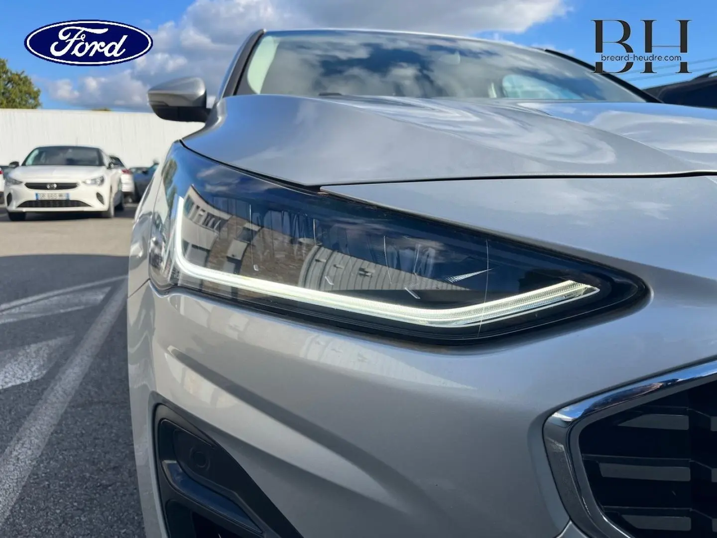 Gros plan sur le phare avant droit de la Ford Focus 2023 gris lunaire métallisé avec calandre chromée visible.