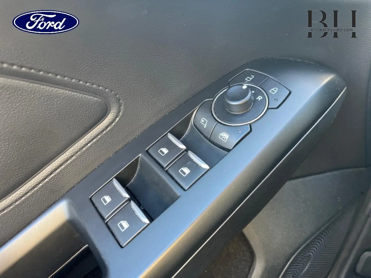 Gros plan sur la commande des vitres et rétroviseurs côté conducteur de la Ford Focus gris lunaire 2023.