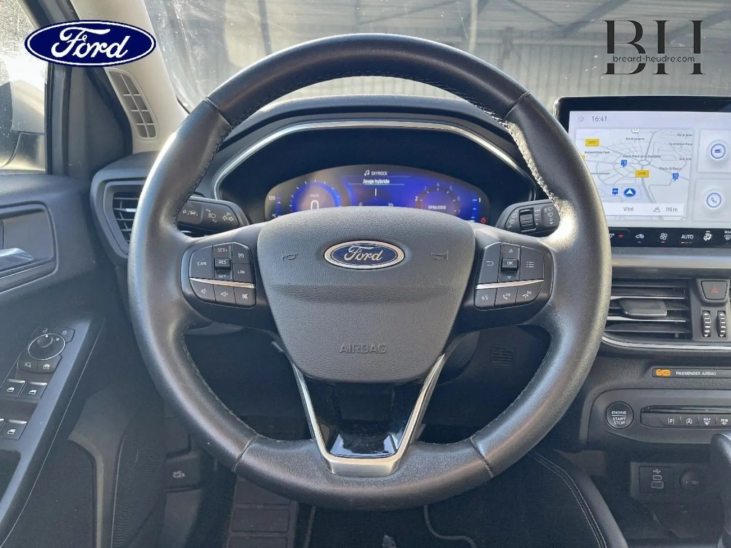 Vue intérieure centrée sur le volant cuir multifonction de la Ford Focus 2023 avec tableau de bord numérique et écran tactile.