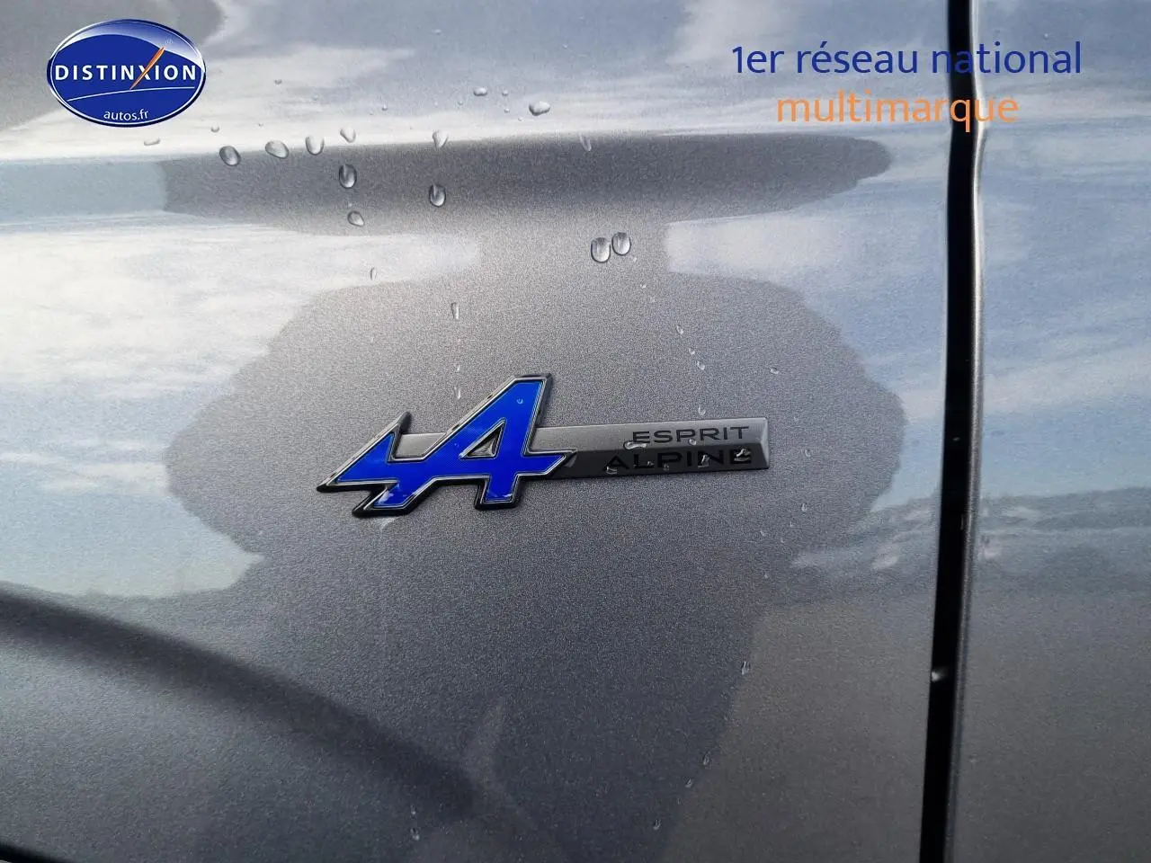 Gros plan sur l'écusson Esprit Alpine bleu sur la carrosserie gris schiste du Renault Espace VI hybride 2025