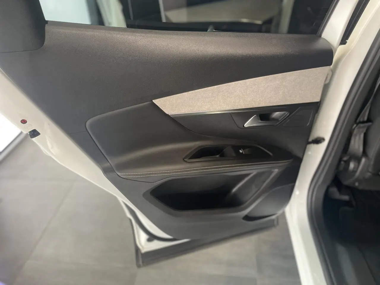 Vue rapprochée de la porte arrière droite blanche nacrée du Peugeot 3008 GT avec insert gris clair et garniture noire.