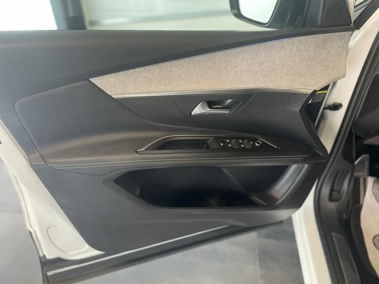 Vue intérieure côté gauche de la porte avant blanche nacrée du Peugeot 3008 GT avec garniture noire et inserts gris.