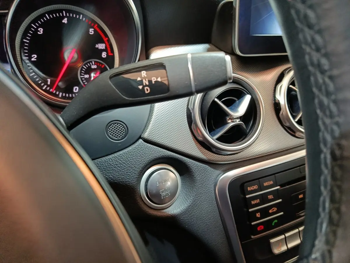 Détail intérieur du tableau de bord gris d’une Mercedes GLA 200 d, avec bouton démarrage et commandes de boîte auto visibles.
