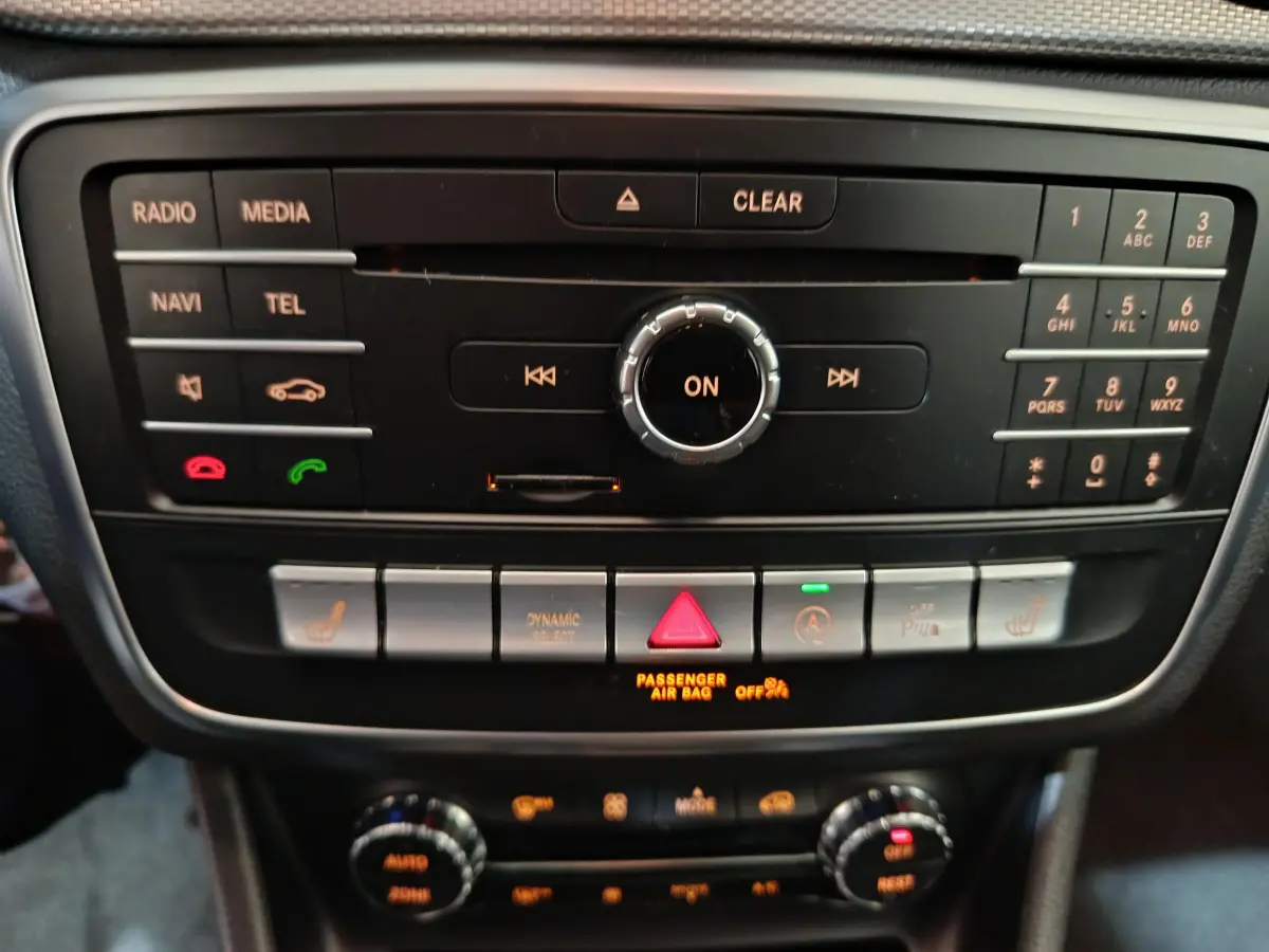 Gros plan sur la console centrale noire du Mercedes GLA 200 d Business Executive gris clair, avec commandes multimédia et climatisation.