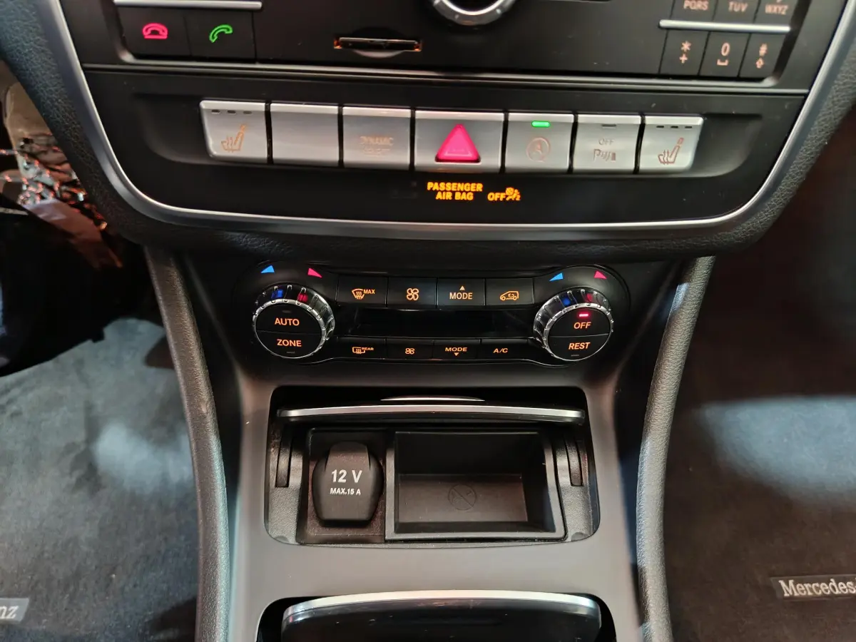 Vue rapprochée de la console centrale du Mercedes GLA 200 d gris clair, avec commandes climatisation et prise 12V visibles.
