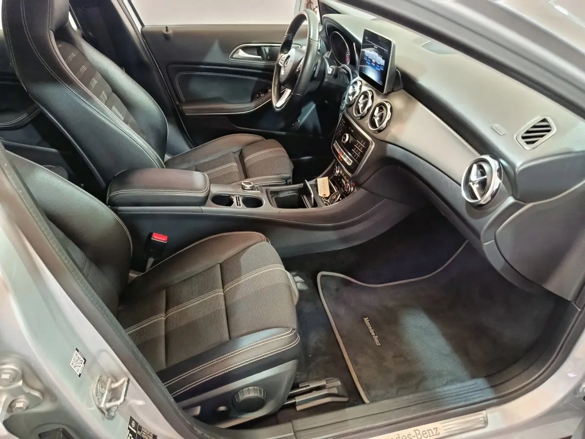 Vue intérieure côté conducteur du Mercedes GLA 200 d gris clair, avec sièges tissu noir et tableau de bord moderne.