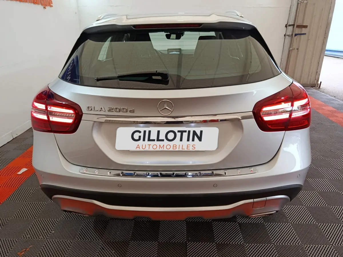 Vue arrière d'un Mercedes GLA 200 d gris clair avec feux LED allumés et logo Mercedes visible sur le hayon.