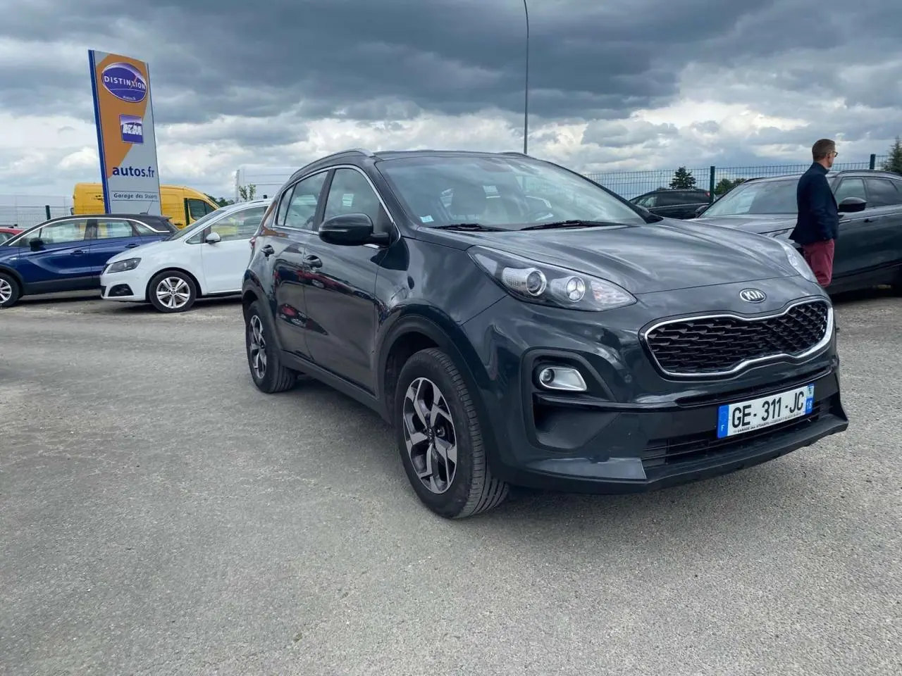 KIA Sportage gris foncé en 3/4 avant droit, avec jantes alliage noires et calandre distinctive Black Edition.