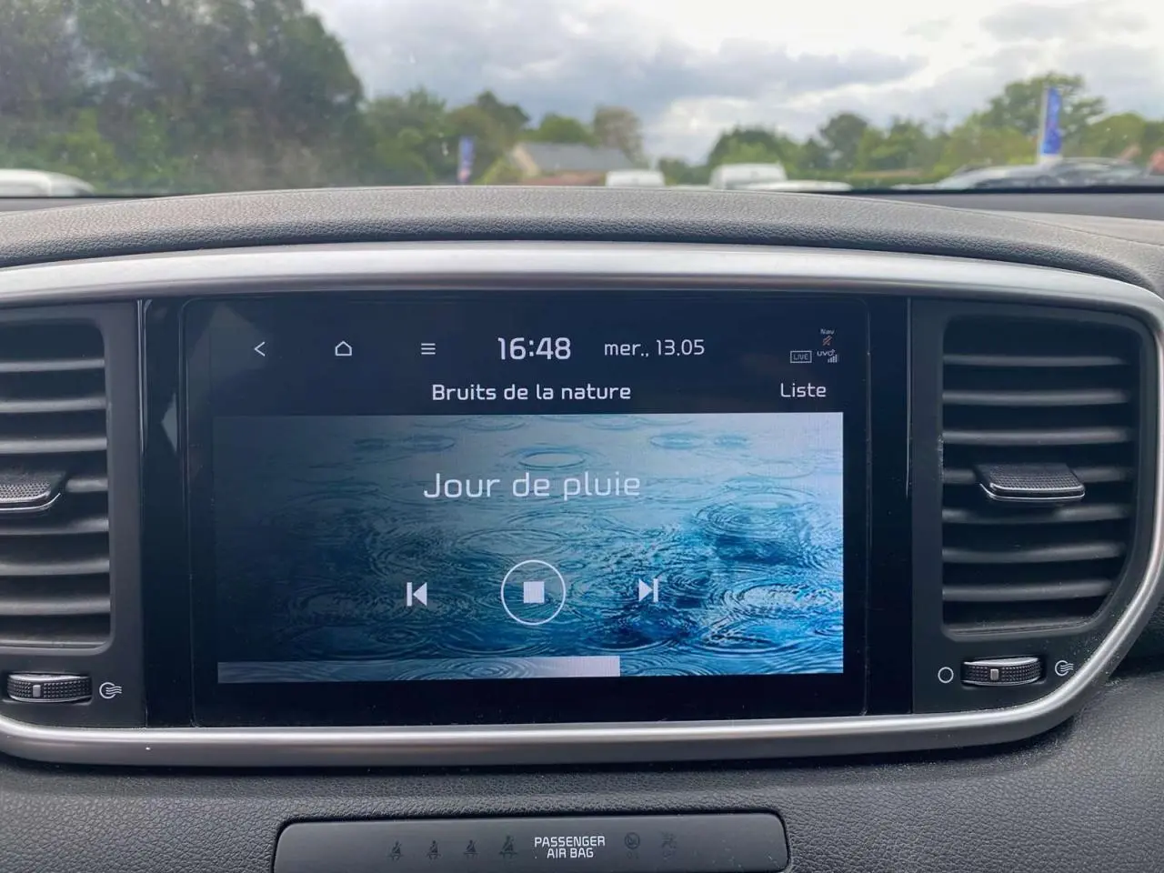 Écran tactile central 8 pouces du Kia Sportage 2021, affichant une ambiance sonore "Jour de pluie" dans un intérieur noir.