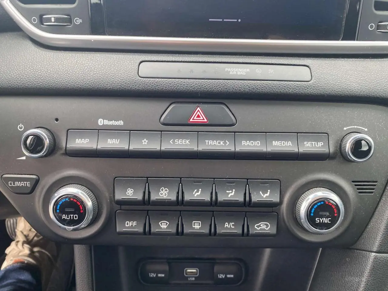 Tableau de bord du Kia Sportage 2021, vue frontale centrée sur la console avec commandes climatisation et multimédia.
