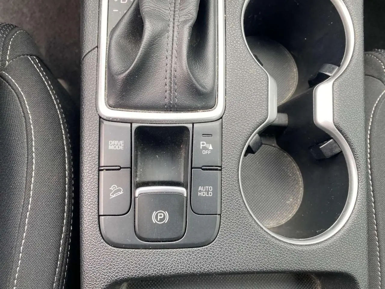Vue rapprochée de la console centrale du Kia Sportage 2021, montrant le levier de vitesse cuir et les commandes de frein électrique.