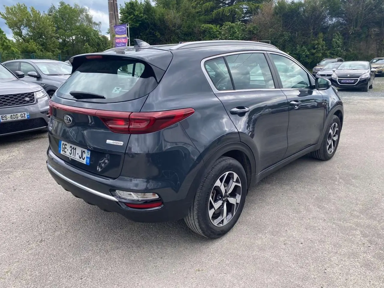 Vue 3/4 arrière droite d’un KIA SPORTAGE gris foncé métallisé avec jantes alliage noires Black Edition.