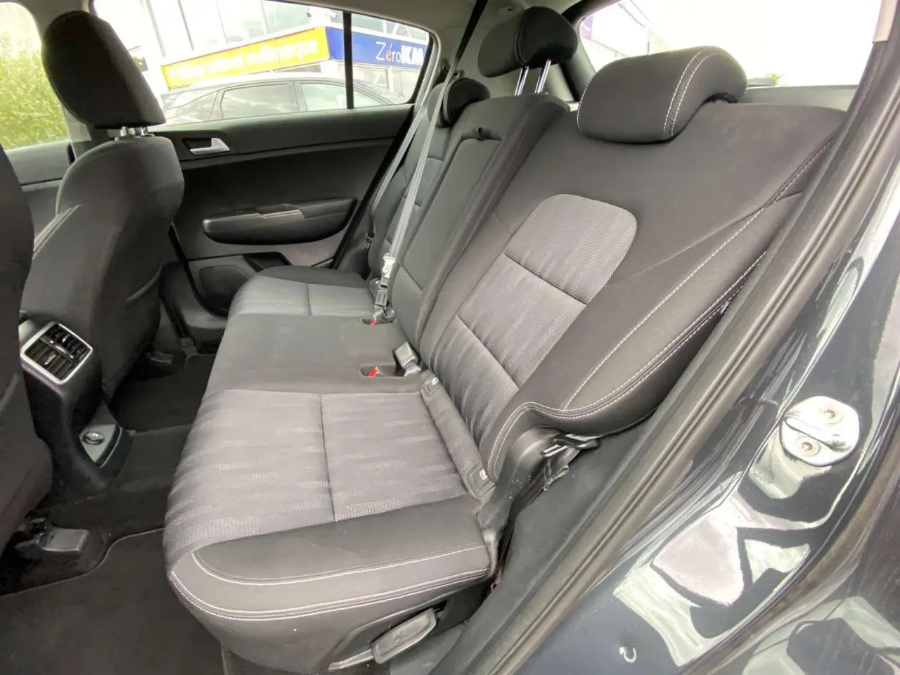 Vue intérieure côté droit de la banquette arrière grise foncée du KIA SPORTAGE 2021 Black Edition avec sellerie tissu et surpiqûres blanches.