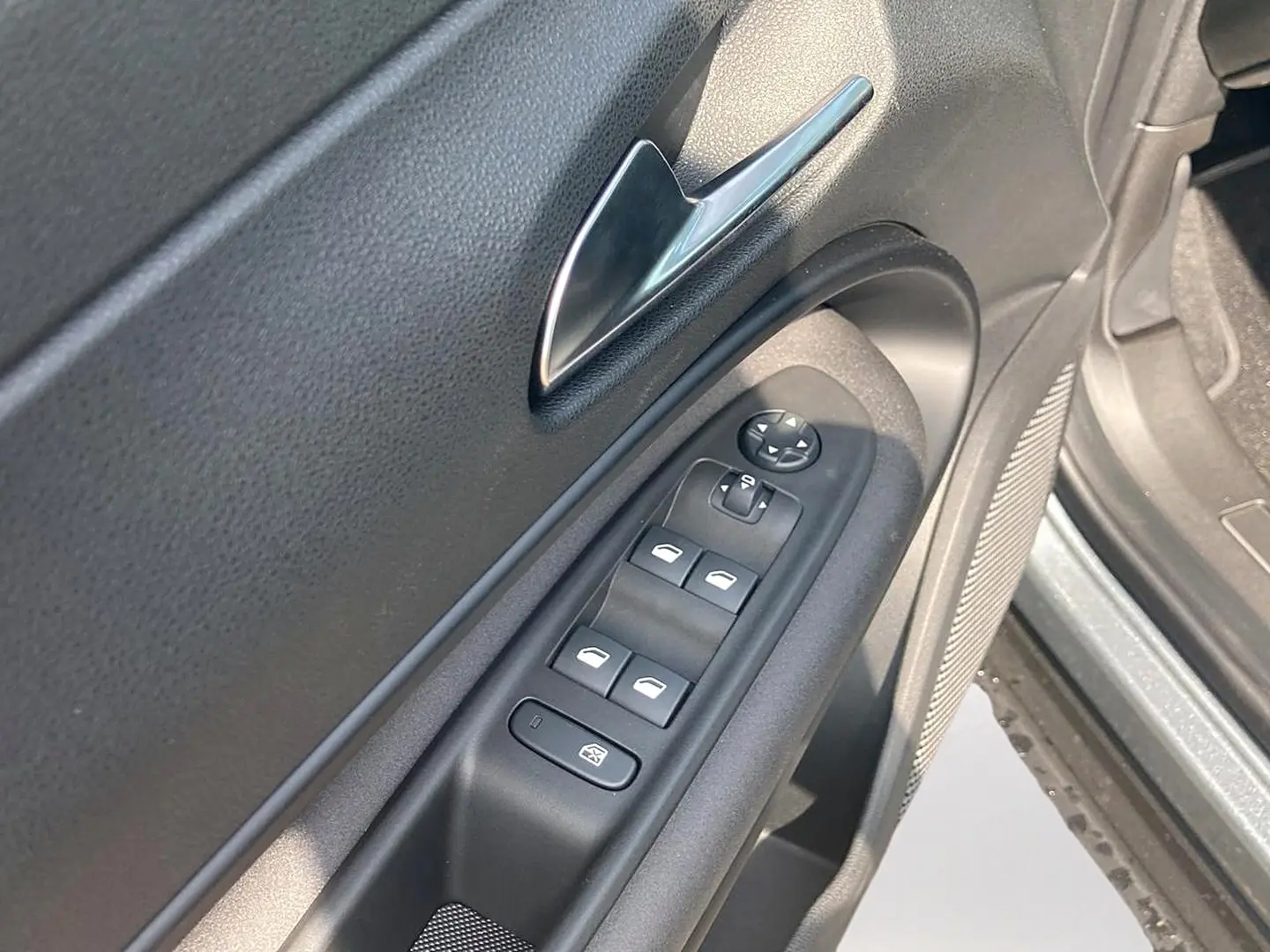 Gros plan sur la commande des vitres et rétroviseurs côté conducteur d'une Alfa Romeo Junior grise, intérieur noir.