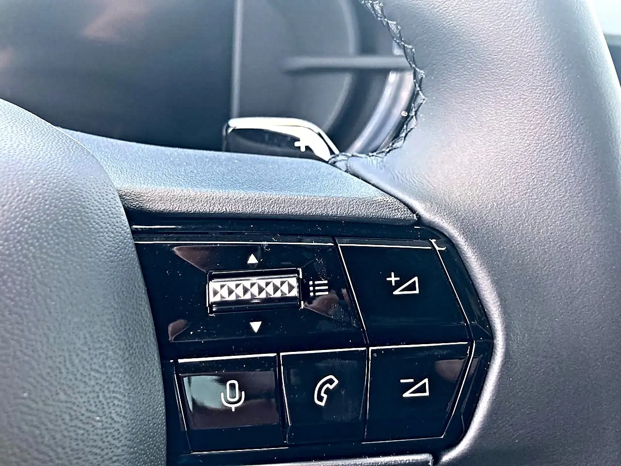 Gros plan sur les commandes du volant côté droit de l'Alfa Romeo Junior gris, avec boutons de volume et appels.