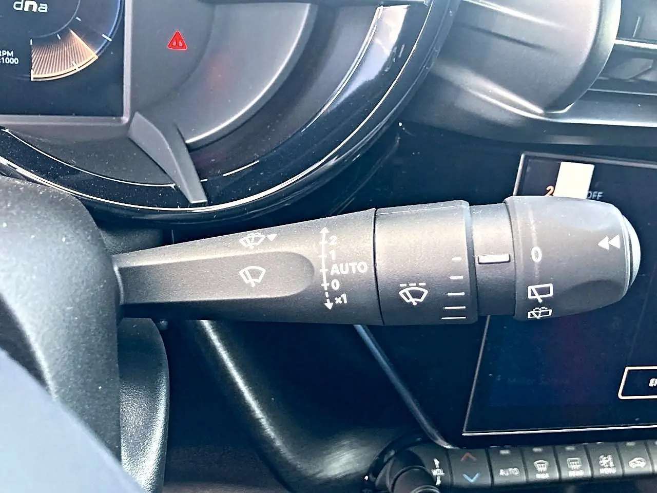 Gros plan sur la commande des essuie-glaces à gauche du volant dans l’habitacle gris de l’Alfa Romeo Junior 1.2 hybride 2026.