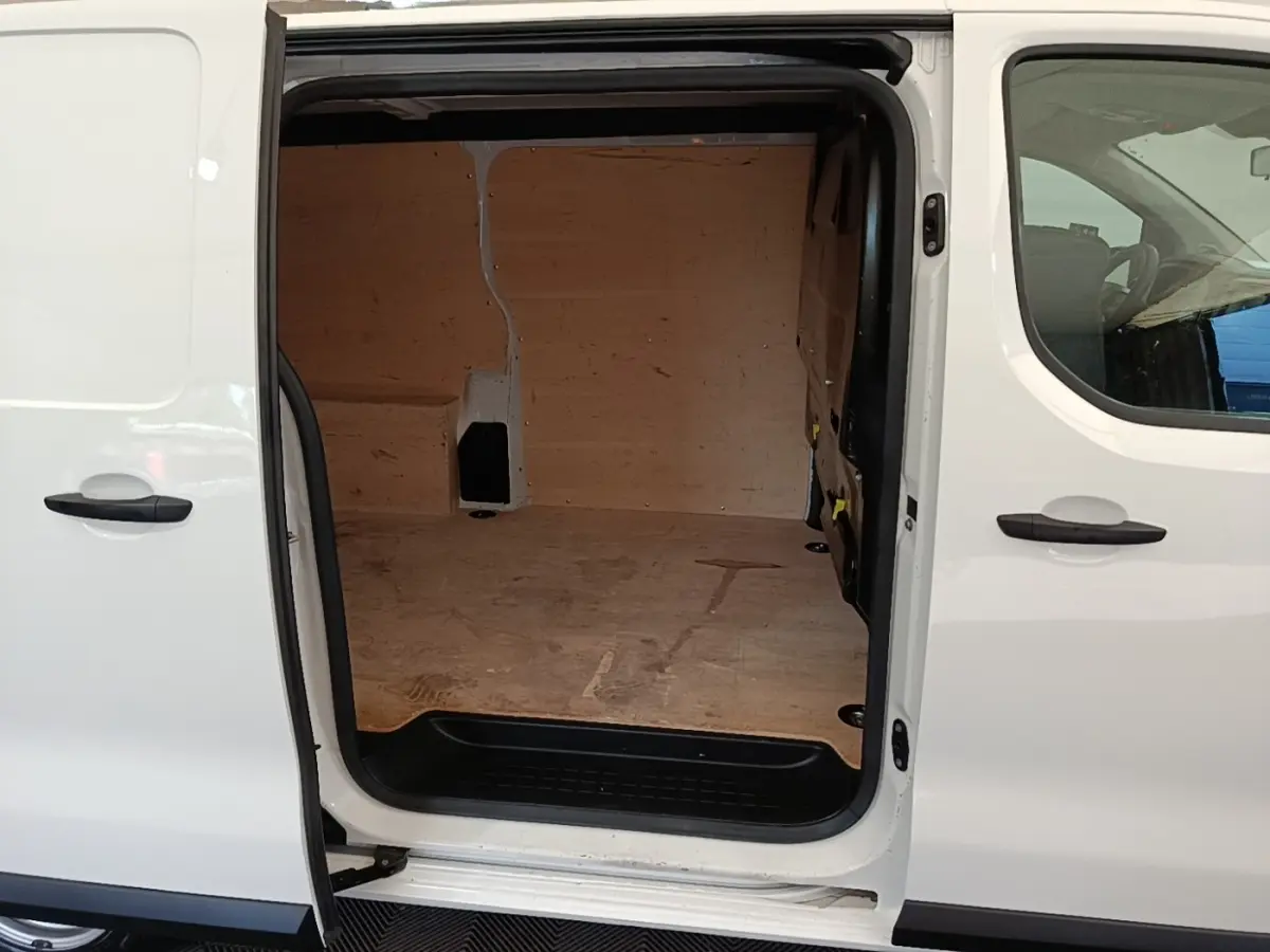 Vue latérale gauche d’un Peugeot Expert Fourgon blanc avec porte coulissante ouverte dévoilant l’espace de chargement en bois.