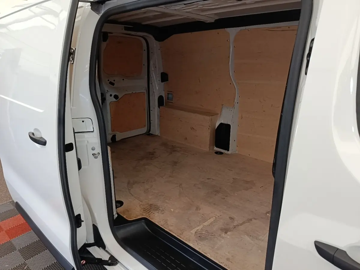Vue intérieure côté droit du fourgon blanc Peugeot Expert avec aménagement bois brut dans l’espace de chargement.