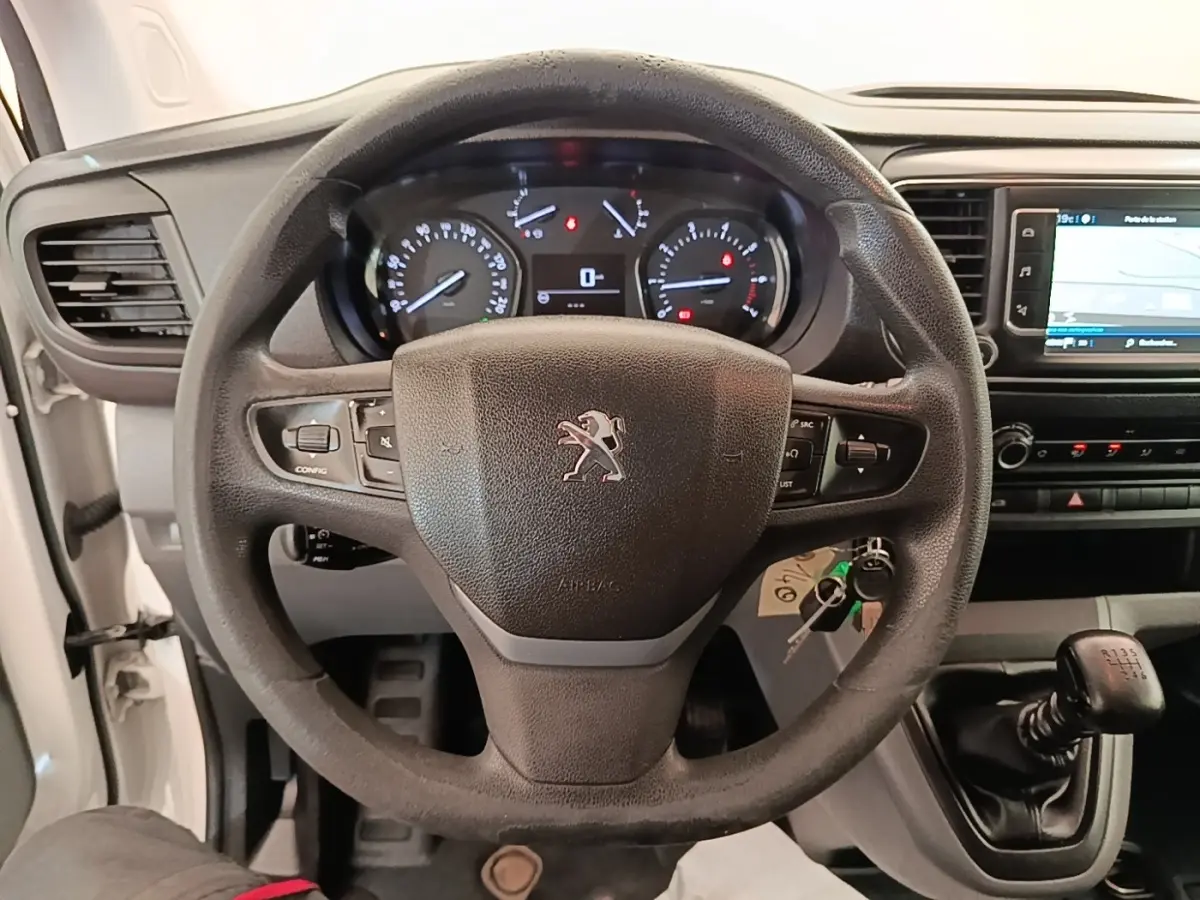 Vue intérieure centrée sur le volant noir Peugeot avec tableau de bord et levier de vitesses manuel visible.