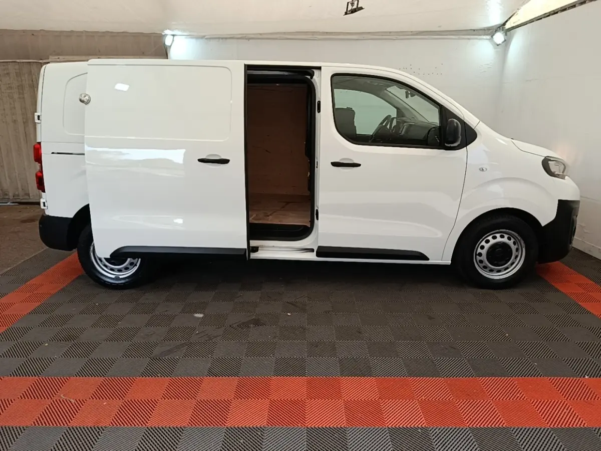 Vue de profil côté droit du Peugeot Expert Fourgon blanc 2020 avec porte latérale coulissante ouverte montrant l'intérieur vide.