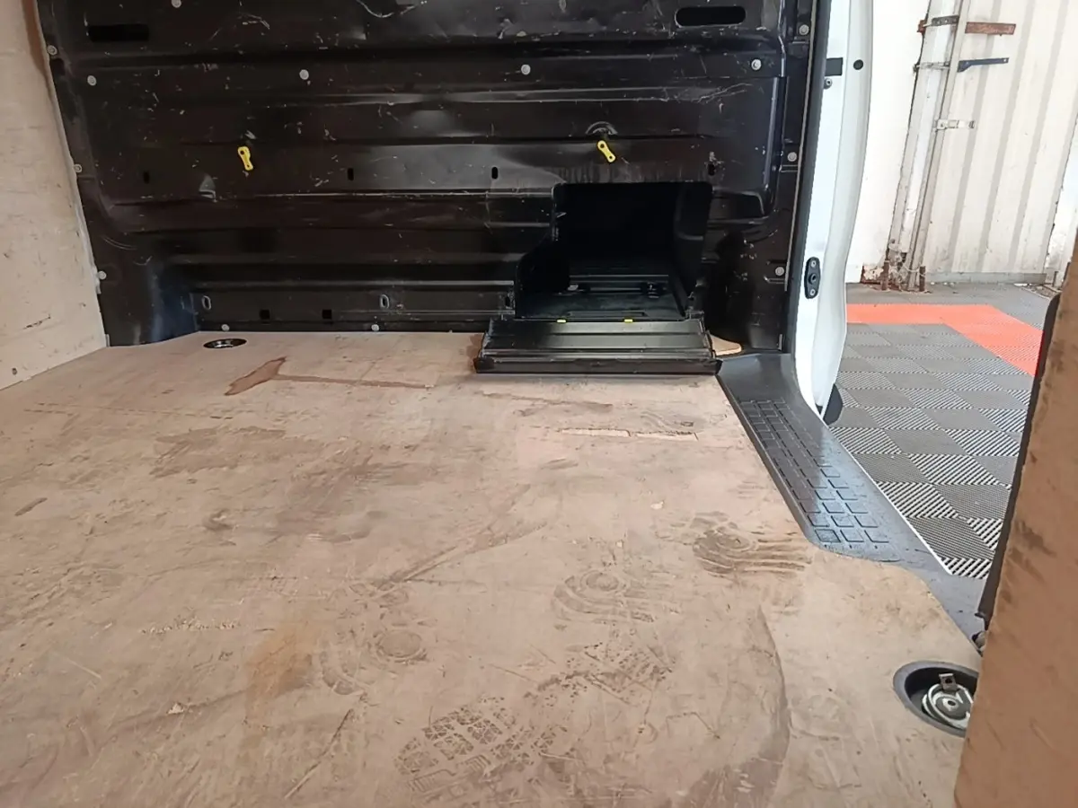 Vue intérieure du coffre arrière du Peugeot Expert Fourgon blanc, montrant le plancher en bois et la cloison pleine noire.