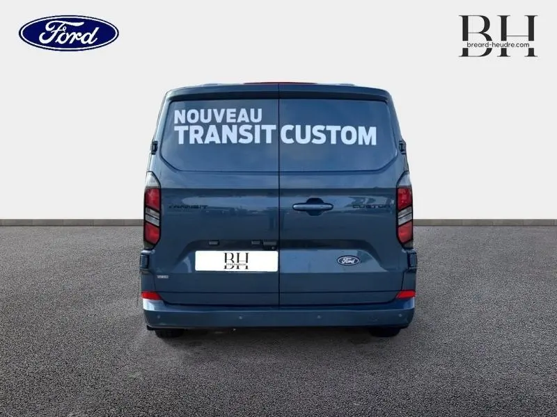 Vue arrière du fourgon Ford Transit Custom bleu azur métallisé avec marquage "Nouveau Transit Custom" sur les portes arrière.