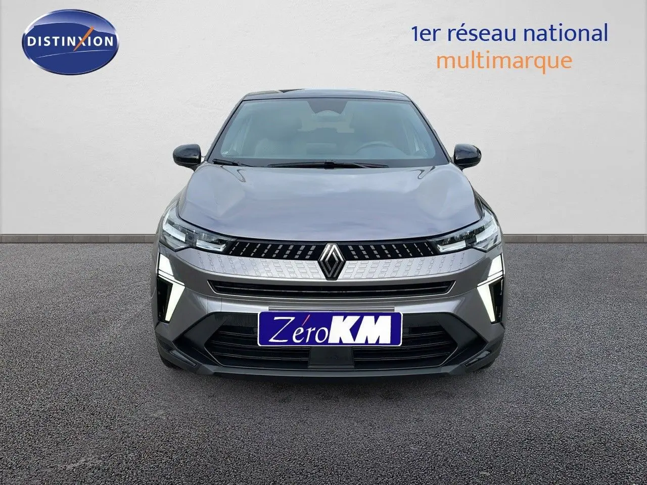 Vue frontale du Renault Captur E-Tech hybride gris Cassiopée avec toit noir, feux LED allumés et calandre moderne.
