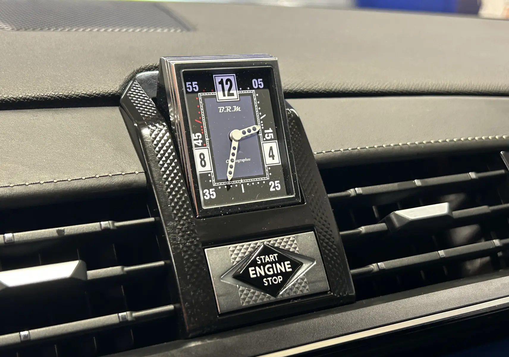 Gros plan sur l'horloge B.R.M et le bouton Start Engine du tableau de bord noir du DS7 BlueHDI 130 2024.