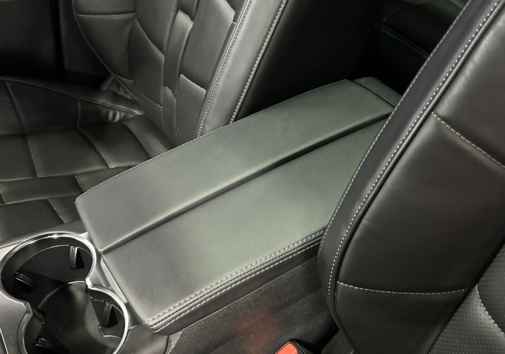 Gros plan sur l'accoudoir central et les sièges en cuir noir du DS7 BlueHDI 130 EAT8 OPERA 2024.