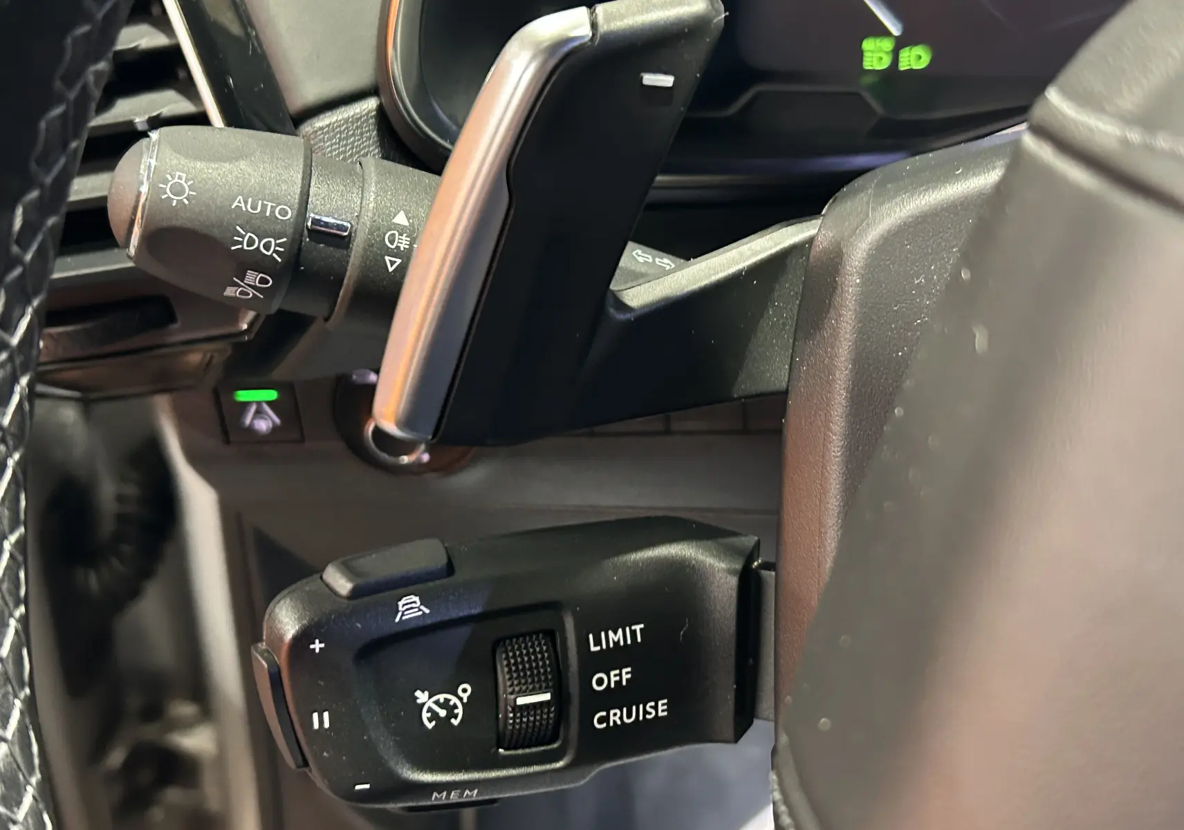 Gros plan sur les commandes du régulateur de vitesse à gauche du volant du DS7 2024 couleur Chrystal pearl.