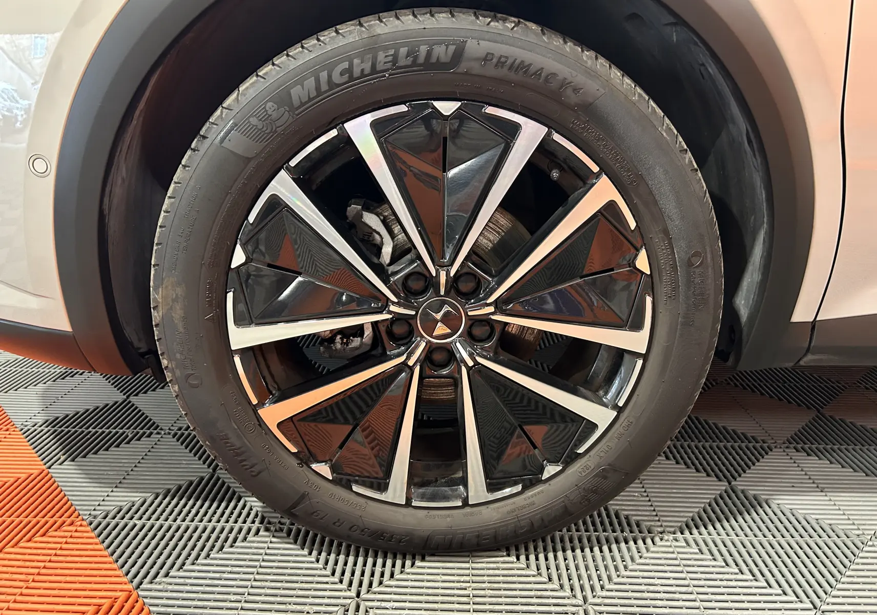 Gros plan sur la roue avant gauche du DS7 2024 Chrystal pearl, jante alliage noire et argent avec pneu Michelin Primacy.