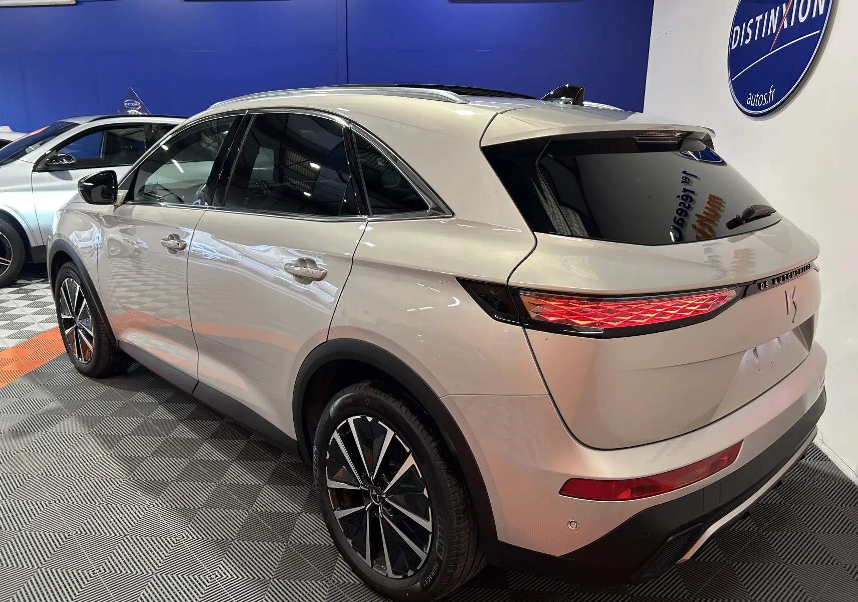 DS7 BlueHDI 130 en Chrystal pearl, vue 3/4 arrière droit, hayon électrique et toit ouvrant visibles en showroom.