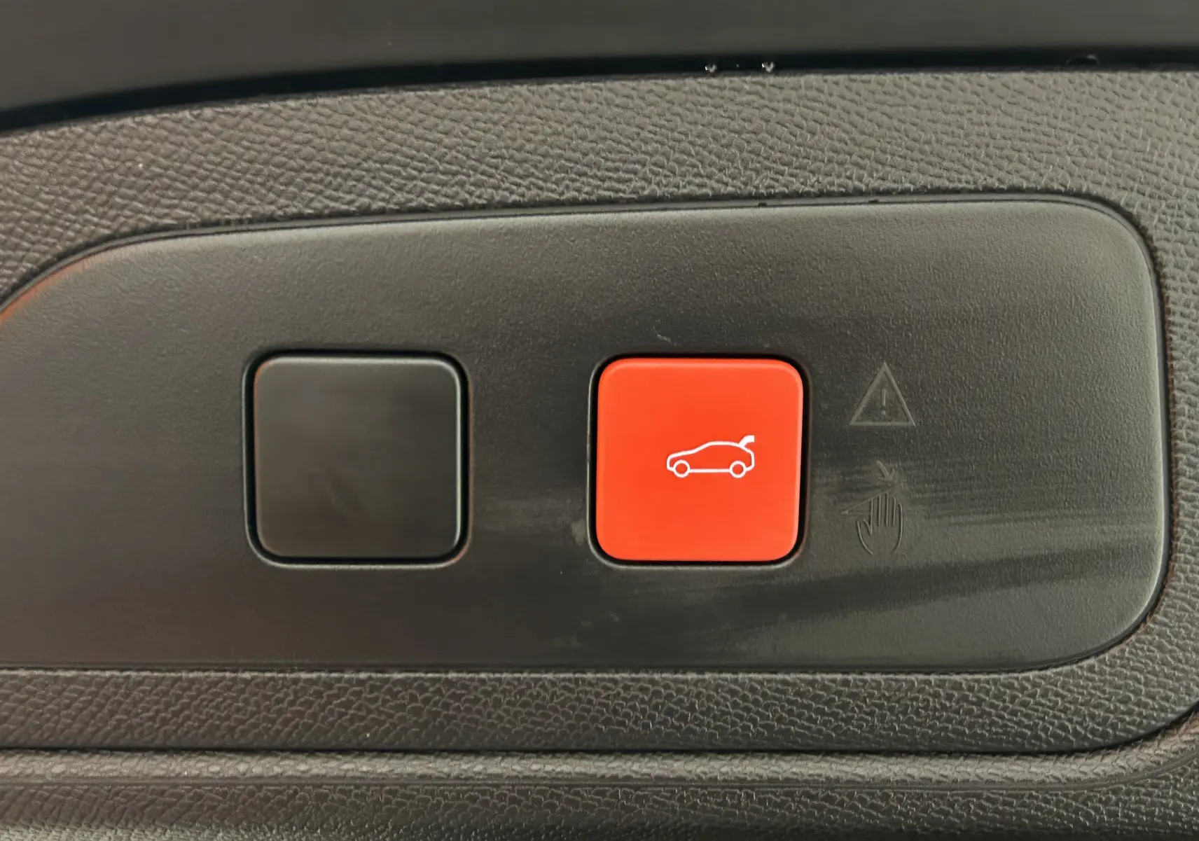 Gros plan sur le bouton rouge d'ouverture électrique du hayon dans l'habitacle du DS7 BlueHDI 130 EAT8 Opera Chrystal Pearl 2024.