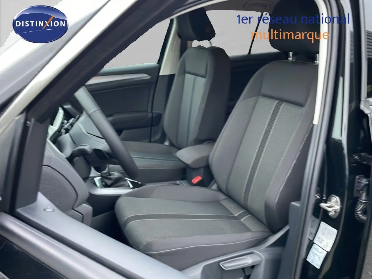 Vue intérieure côté gauche du Volkswagen T-Roc noir Grenadilla, mettant en valeur les sièges tissu avec détails gris et volant multifonction.