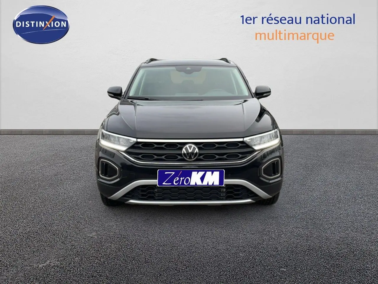 Vue frontale d'un Volkswagen T-Roc noir Grenadilla métallisé avec calandre distinctive et feux LED allumés.