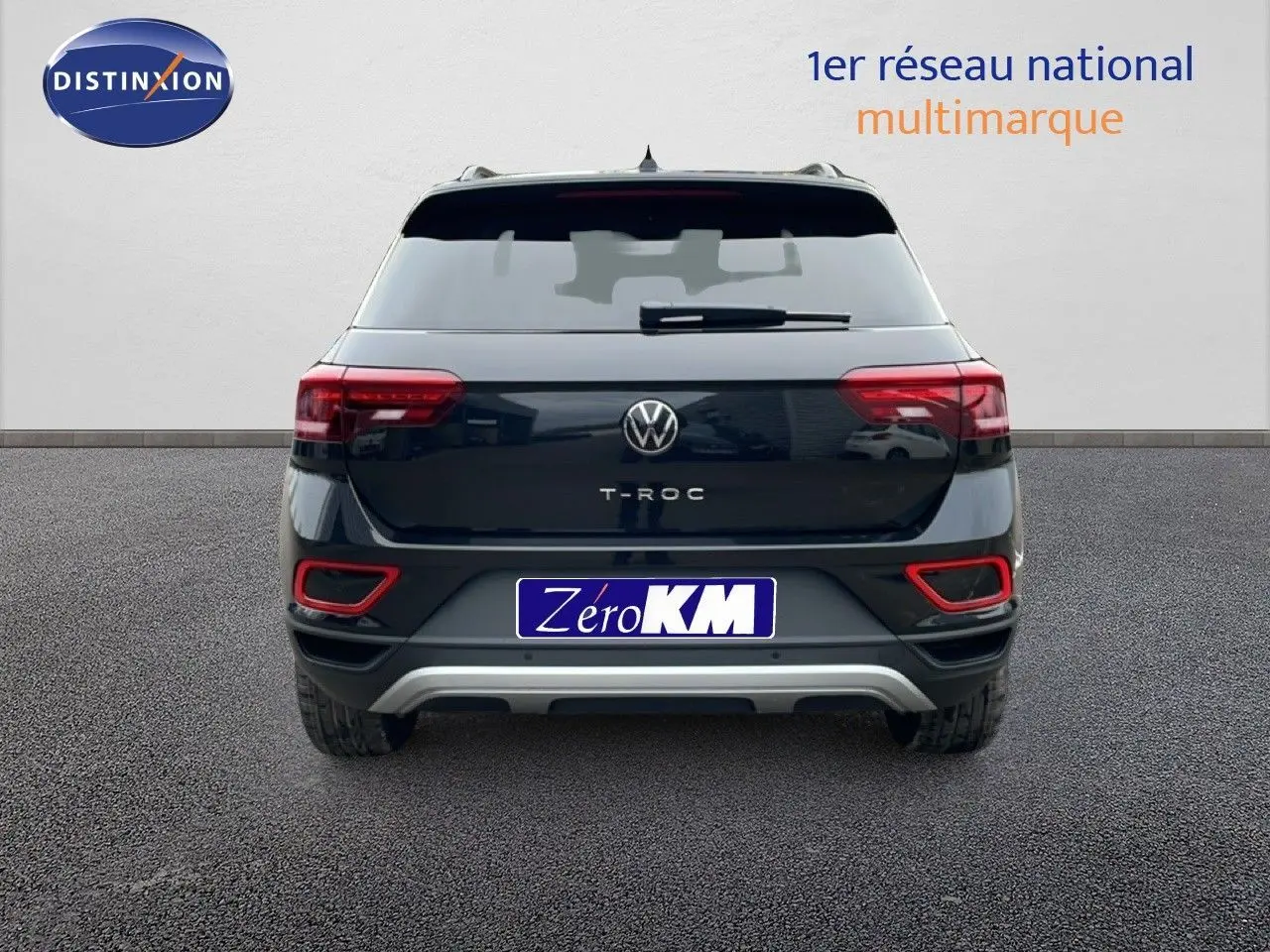 Vue arrière d'un Volkswagen T-Roc noir Grenadilla Metal avec feux arrière allumés et détails rouges sur le pare-chocs.