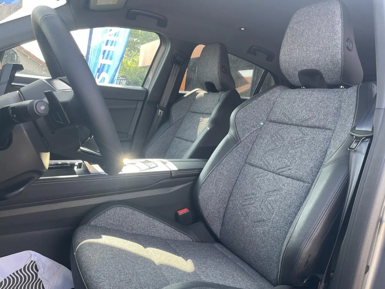 Vue intérieure côté conducteur de la Renault Rafale 2025, sièges sport gris textile avec surpiqûres argentées.