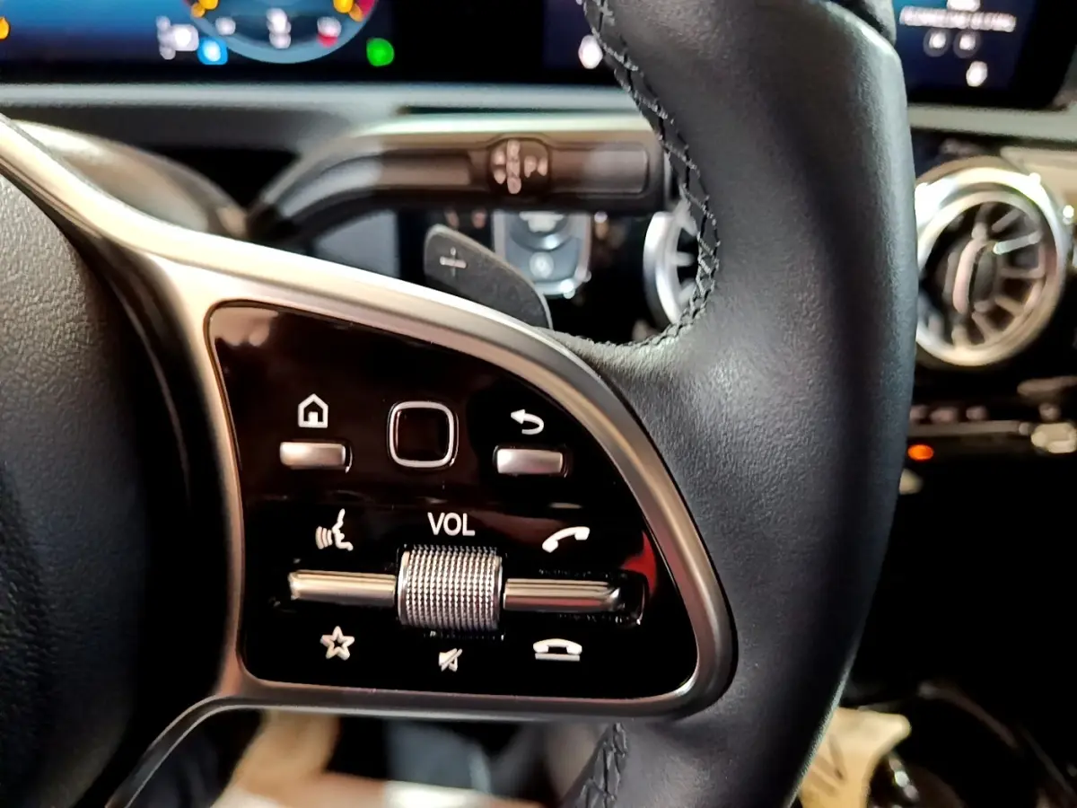 Gros plan sur les commandes multifonctions en cuir noir du volant de la Mercedes Classe A Berline A 200 d 2022.