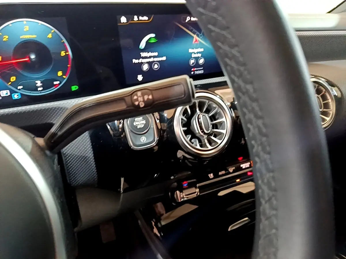 Vue rapprochée du tableau de bord noir de la Mercedes Classe A 200 d, avec écran tactile et aérateurs ronds chromés.