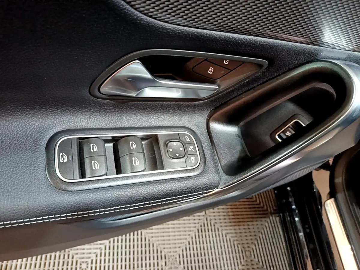 Détail de la porte avant gauche noire de la Mercedes Classe A 2022 avec commandes des vitres et poignée argentée.
