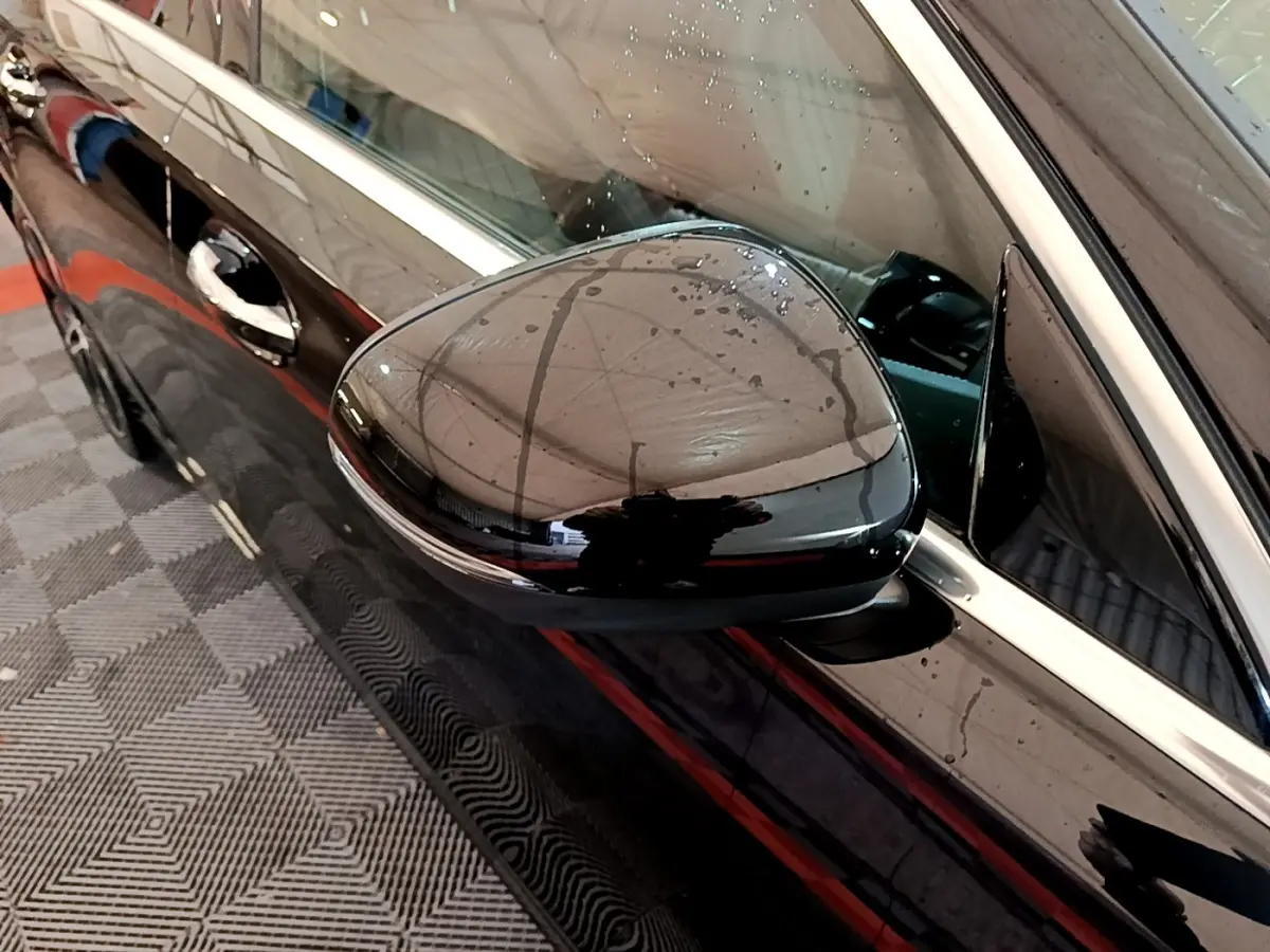 Gros plan sur le rétroviseur côté gauche noir brillant d’une Mercedes Classe A Berline A 200 d Progressive Line 2022.