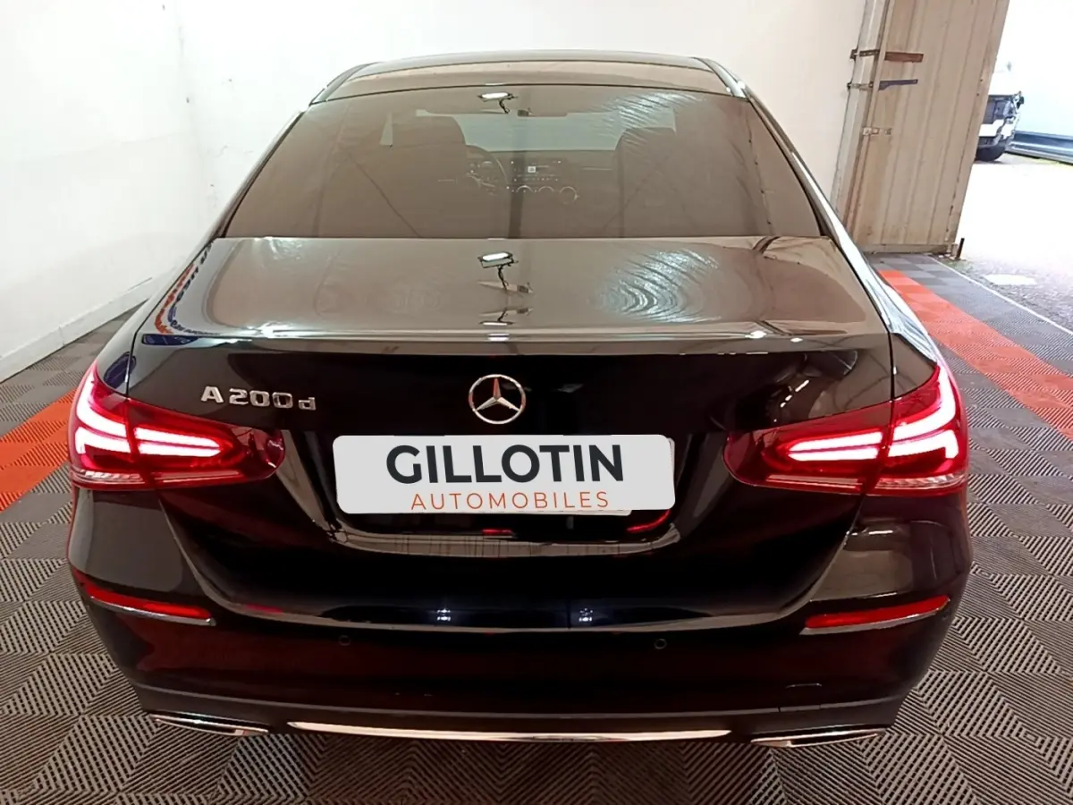 Vue arrière d'une Mercedes Classe A Berline A 200 d noire avec feux LED allumés dans un garage.