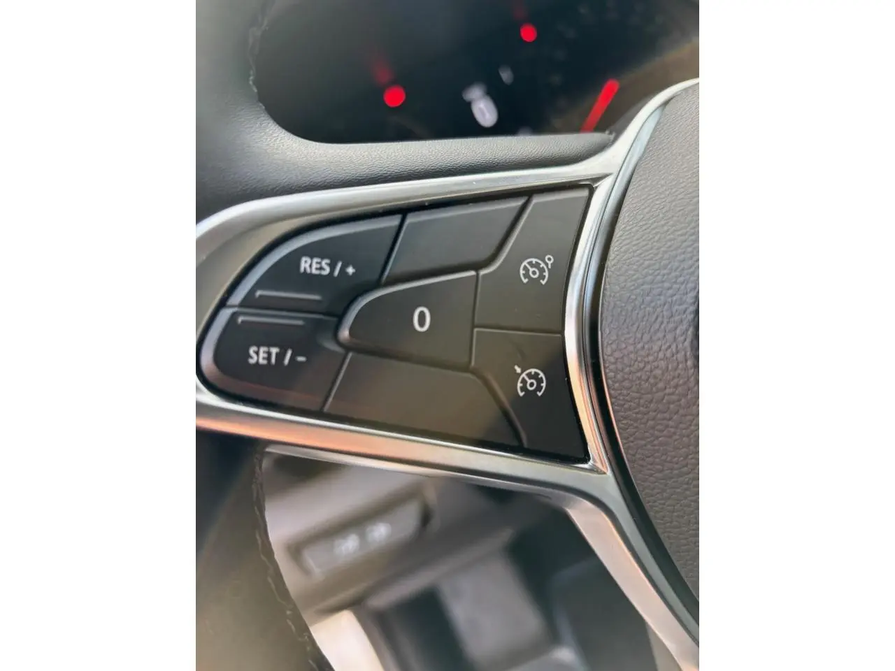 Gros plan sur les commandes du régulateur de vitesse au volant noir du Renault Trafic Fourgon gris clair 2022.