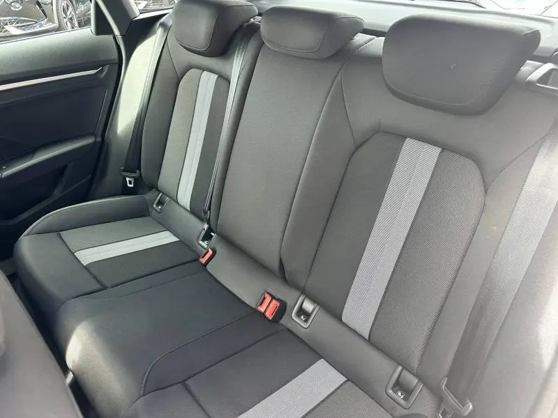 Vue intérieure de la banquette arrière en tissu noir et gris de l'Audi A3 Sportback 2024, avec ceintures et appuie-têtes.