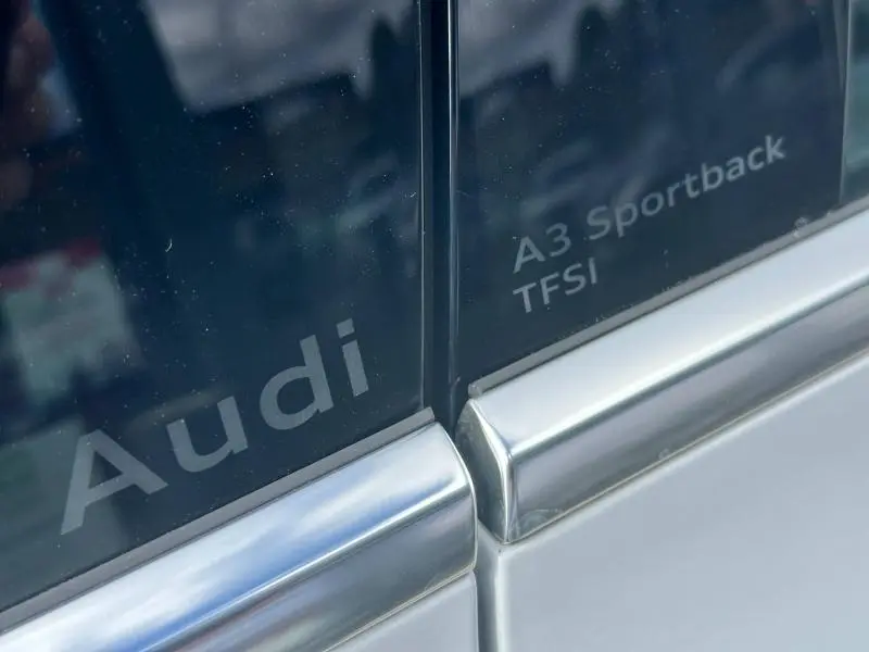 Gros plan sur les vitres arrière d’une Audi A3 Sportback blanche avec logos Audi et A3 Sportback TFSI visibles.