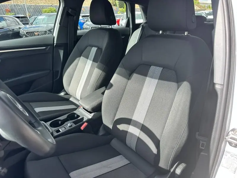 Vue intérieure côté avant droit de l'Audi A3 Sportback 30 TFSI 116ch, sièges tissu noir avec bandes grises centrales.