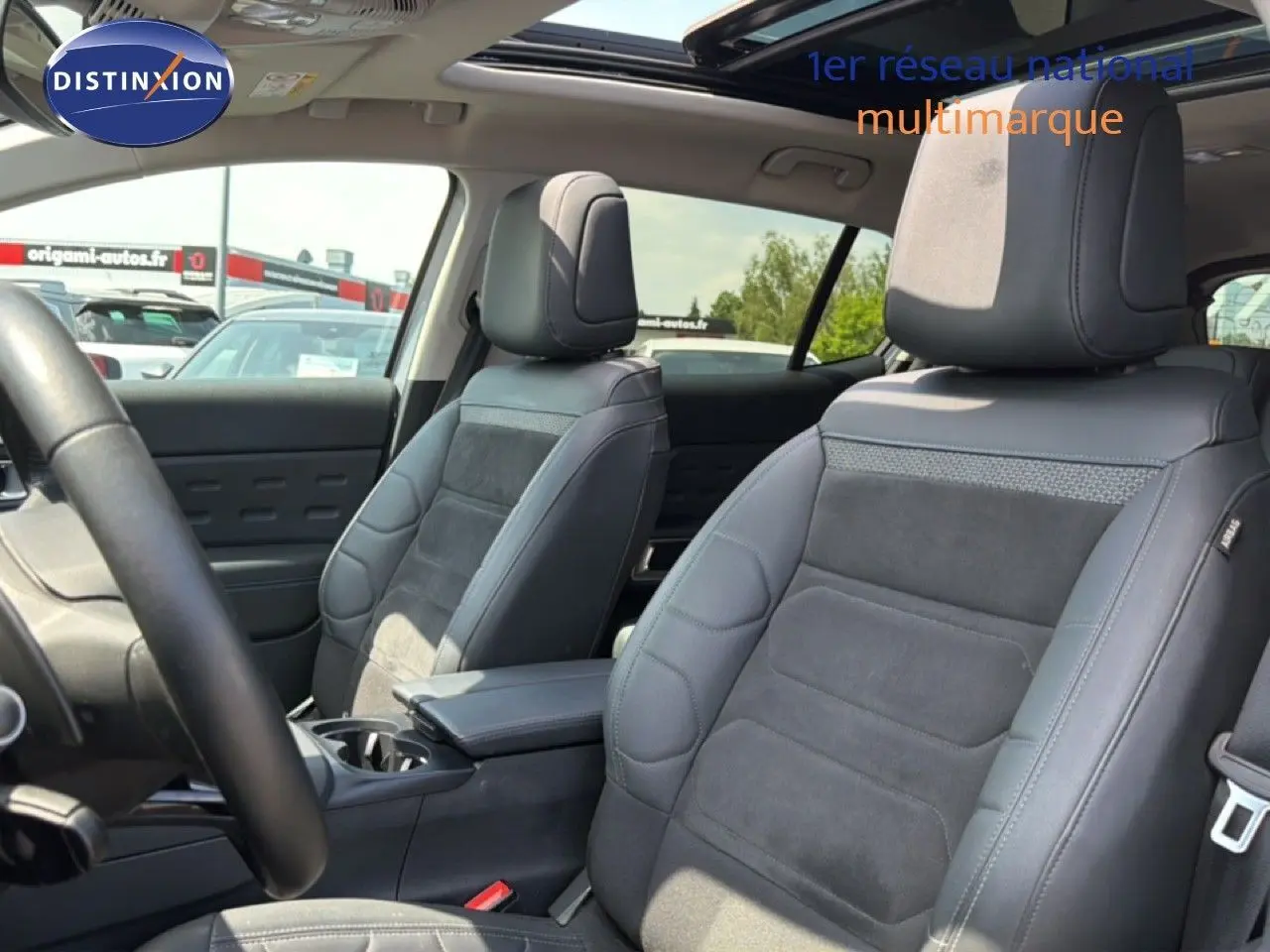 Vue intérieure montrant les sièges avant en tissu et cuir noir du Citroën C5 Aircross 2023, avec accoudoir central.